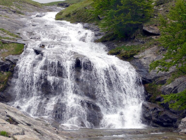Cascata alta in Italia, con acque che scendono fragorosamente in un paesaggio naturale mozzafiato.