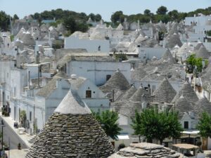 Trullo immerso nella natura della Valle d'Itria, con paesaggi verdi e colline sullo sfondo.